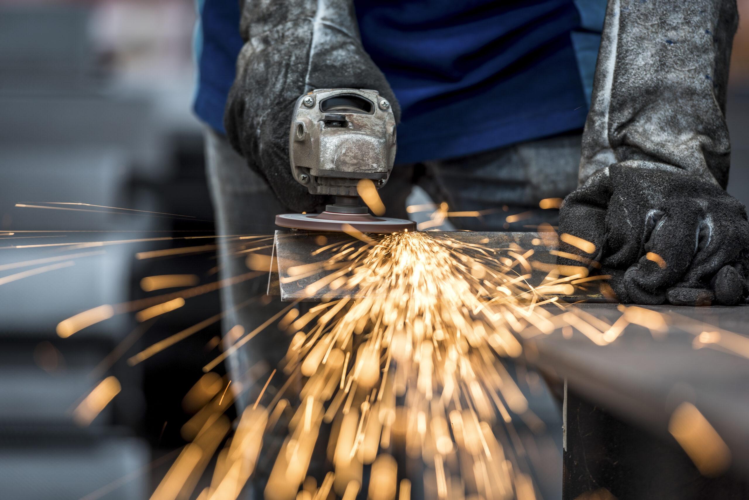 An industrial construction worker using a grinder